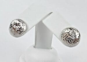 Silver textured earrings on display stand.