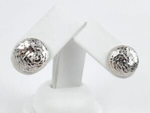 Silver textured dome earrings on display stand.