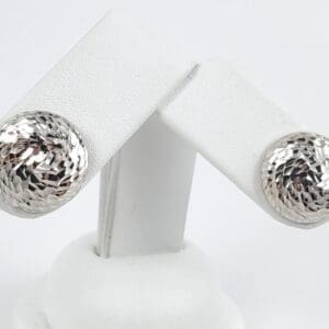 Silver textured dome earrings on display stand.