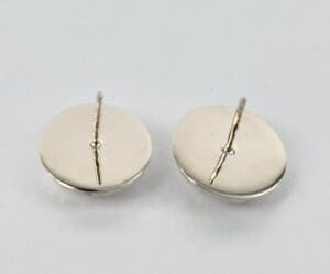 Two silver round cufflinks on white background.