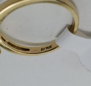 Gold ring with engraved markings and tag.
