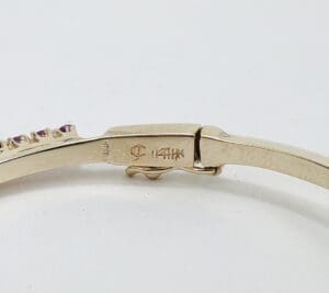 Gold bracelet with gemstone detail and clasp.