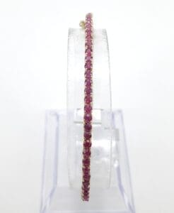 Gold bangle with pink gemstones display.