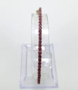 Ruby-studded hoop earring on clear stand.