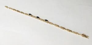Gold bracelet with dark gemstone accents.