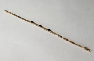 Gold bracelet with dark gemstone accents.