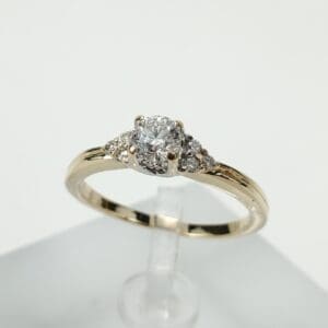 Gold engagement ring with diamond centerpiece displayed.