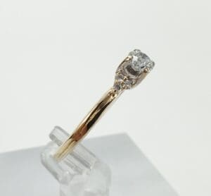 Gold ring with diamond on display stand.