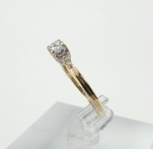 Gold ring with diamond on display stand.