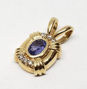 Gold pendant with purple gemstone and diamonds.