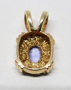 Gold pendant with a purple stone.