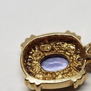 Gold pendant with purple gemstone center.
