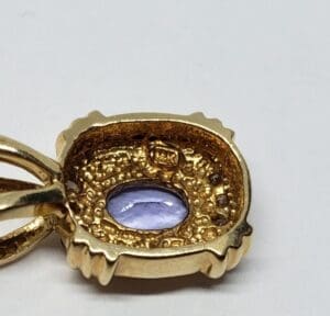 Gold pendant with purple gemstone center.