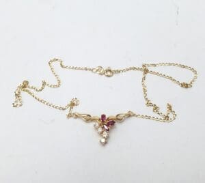 Gold necklace with pink and white stones.