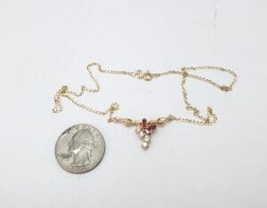Gold necklace with red stones, next to coin.