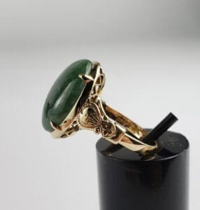 Gold ring with green stone on display.