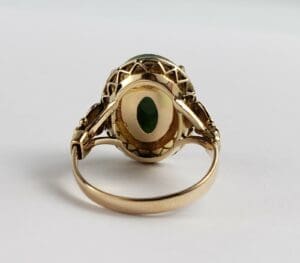 Gold ring with green gemstone, back view.