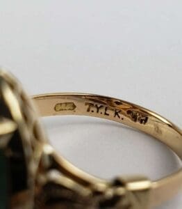 Gold ring with engraved markings and initials.
