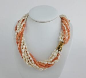 Coral and pearl necklace on display stand.