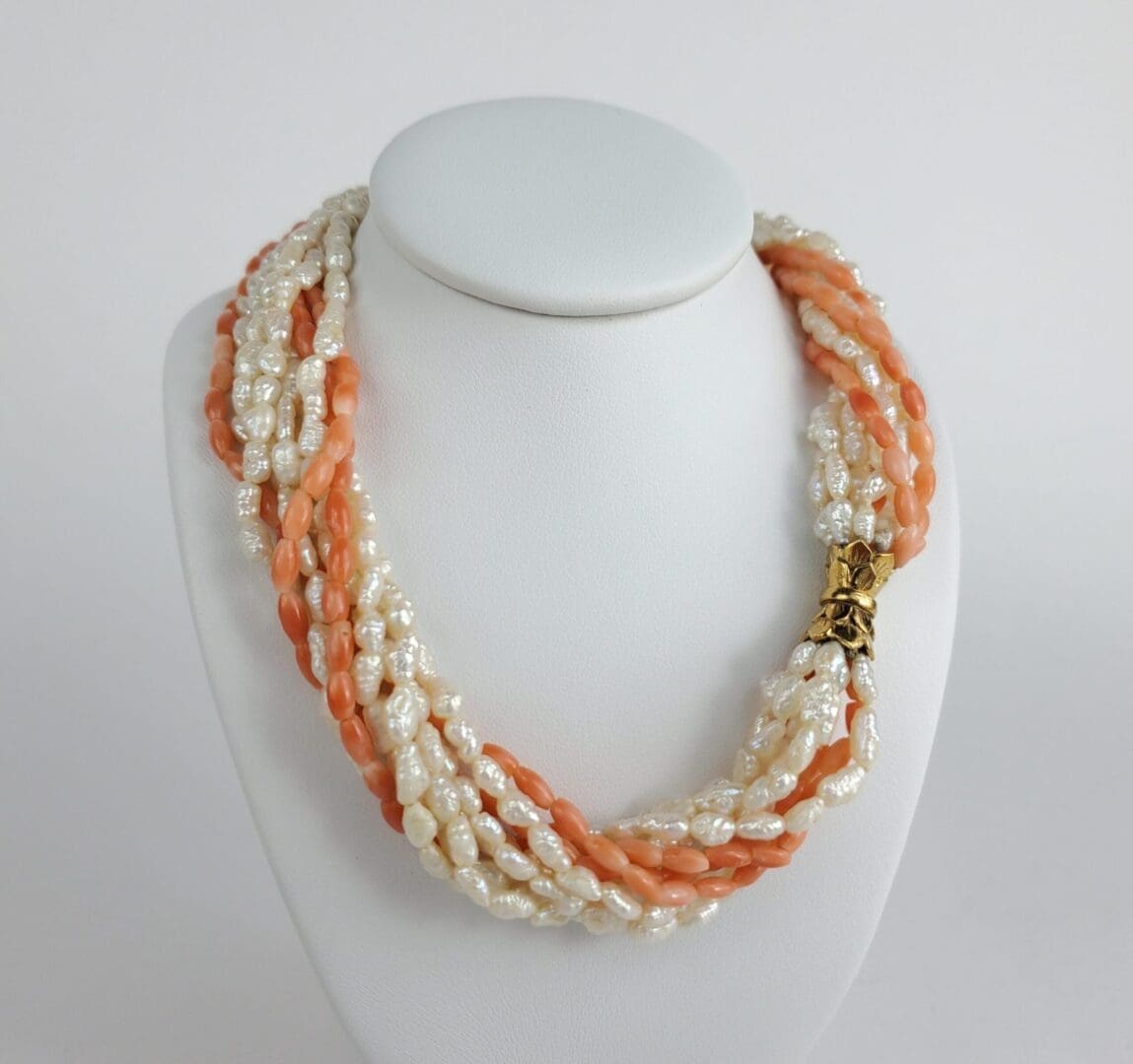 Pearl and coral necklace on display stand.