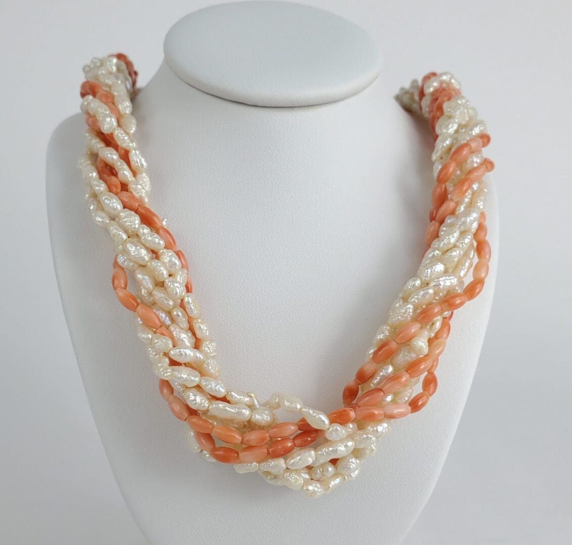 Pearl and coral twisted necklace on display.