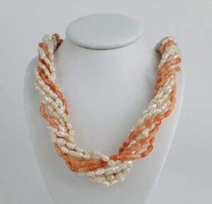 Twisted coral and pearl bead necklace display.