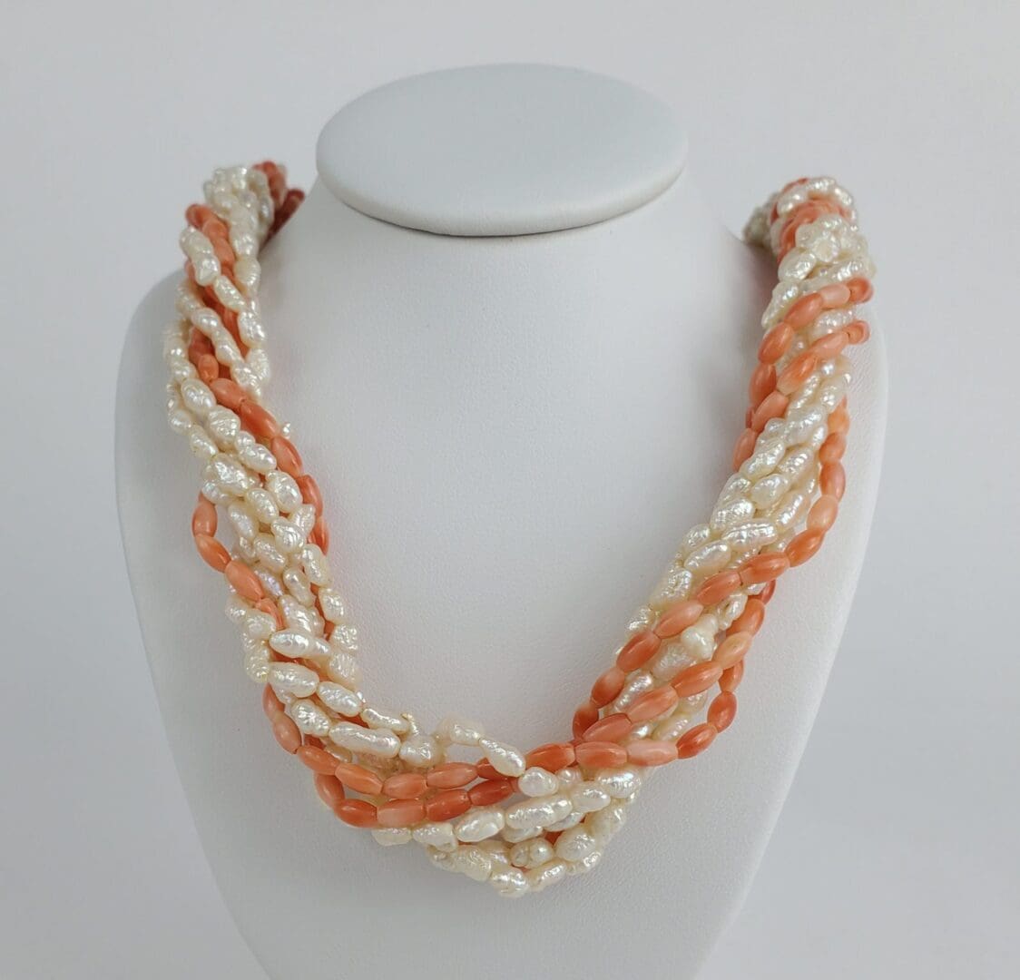 Twisted coral and pearl bead necklace display.