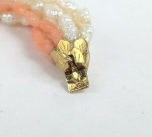 Gold clasp with pearl and coral strands.