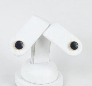 Gold-trimmed black cufflinks on display stand.