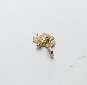 Gold turtle charm on white background.