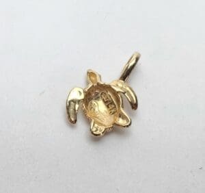 Gold turtle-shaped pendant on white background.