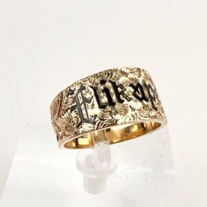 Gold ring with engraved lettering and design.