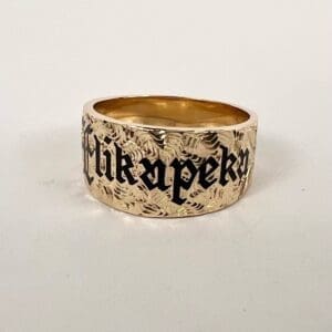 Gold ring with engraved black lettering.