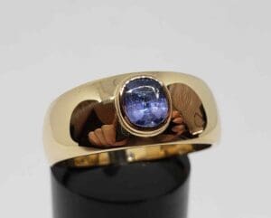 Gold ring with blue gemstone on display.