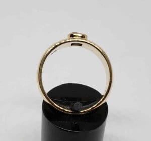 Gold ring on black stand, side view.