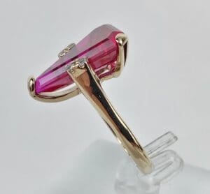 Gold ring with pink gemstone side view.