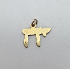 Gold chai pendant on white background.