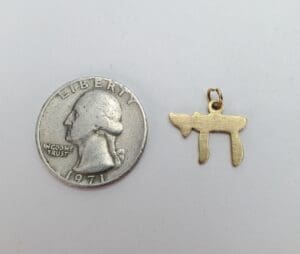Quarter and small gold pendant on white.
