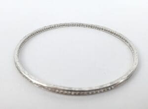 Silver bangle bracelet with intricate design.