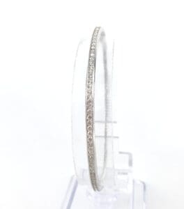 Thin diamond bangle on clear stand.