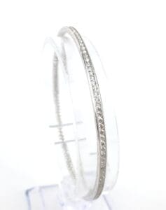 Silver bangle with embedded diamonds on display.