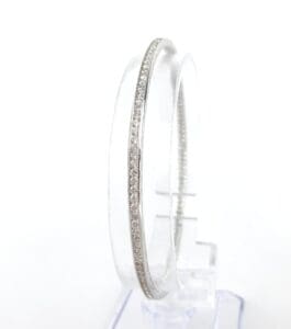 Silver bangle with embedded stones displayed.