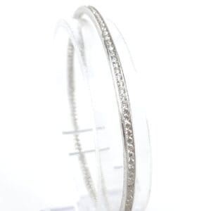 Silver bangle with embedded diamonds on display.
