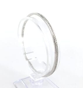 Silver bangle displayed on a clear stand.
