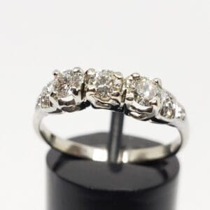 Silver ring with five sparkling diamonds displayed.