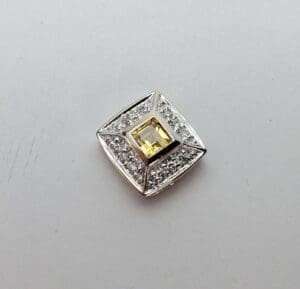 Square diamond brooch with yellow center stone.