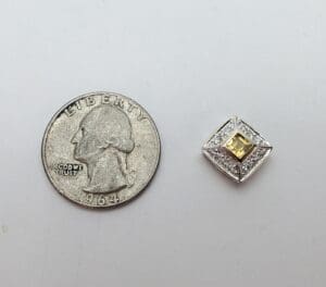 Coin next to a jeweled square brooch.
