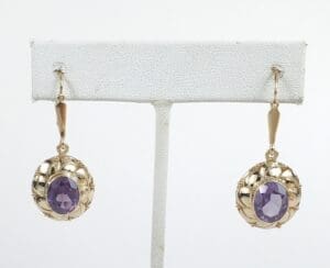 Gold earrings with purple stones displayed.