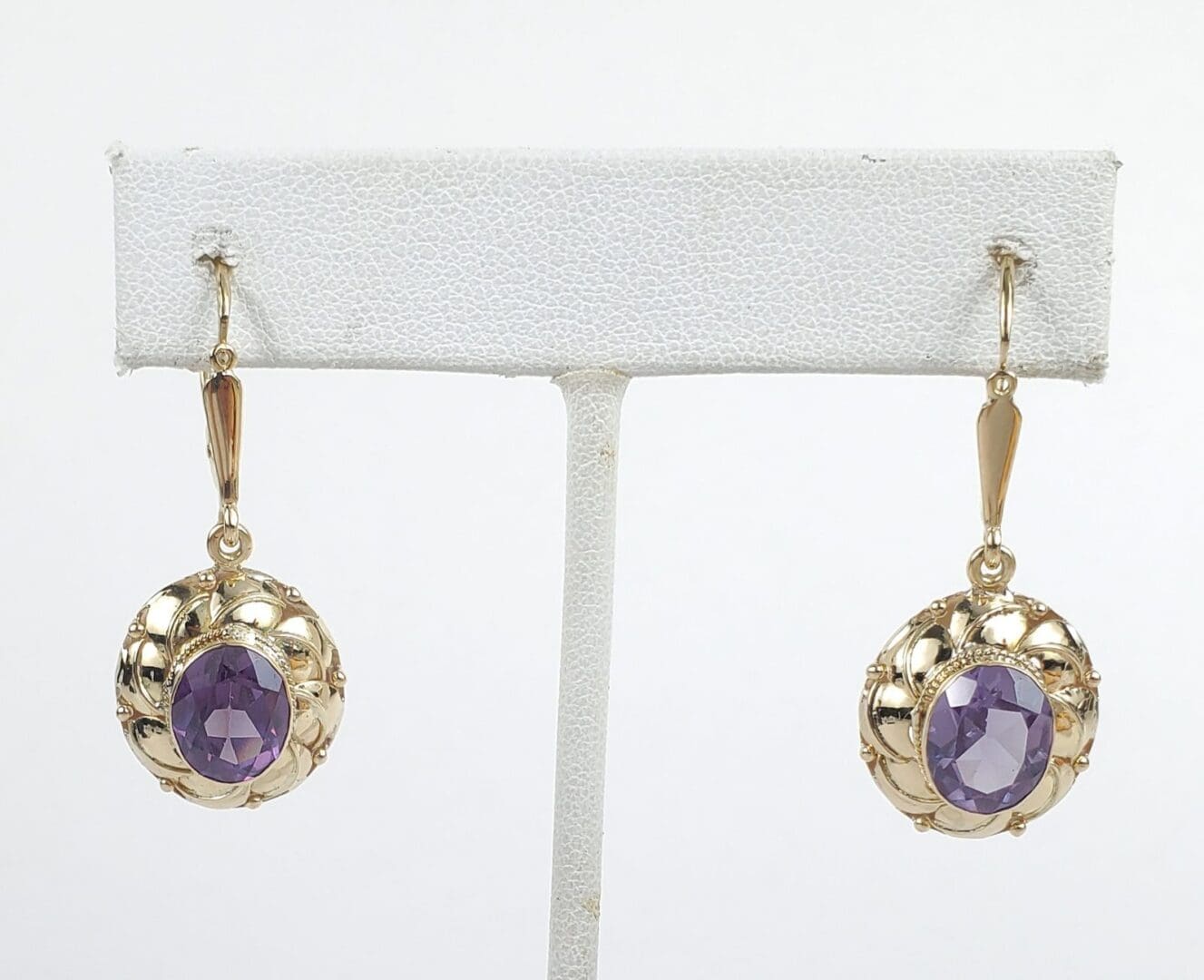 Gold earrings with purple stones displayed.