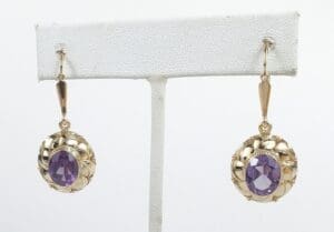 Gold earrings with purple gemstones displayed.